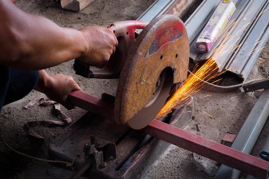 The worker in the workshop cut the steel tube angle grinder, cutting tube.