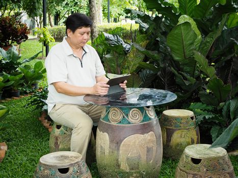 Man finishing work on his tablet and relaxing in the garden.