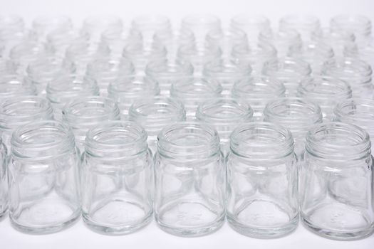 Short glass bottle no cap many glasses row, on white background.