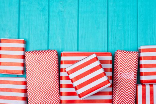 Many gifts in a red and white wrapper on a blue wooden background