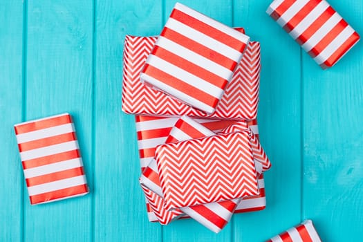 Many gifts in a red and white wrapper on a blue wooden background