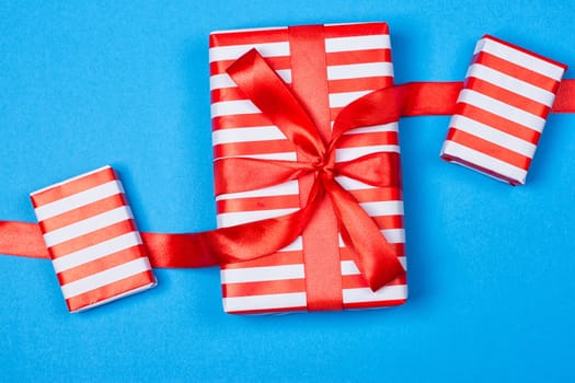 Several neatly laid out gifts in red packing on a blue background. Christmas presents