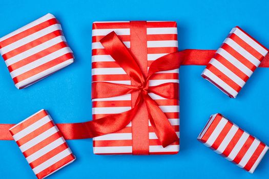 Several neatly laid out gifts in red packing on a blue background. Christmas presents