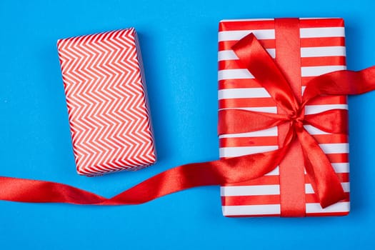 Several neatly laid out gifts in red packing on a blue background. Christmas presents