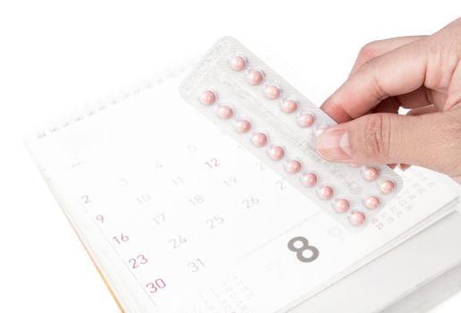 Close up hand hold birth-control pill with date of calendar background, health care and medicine concept