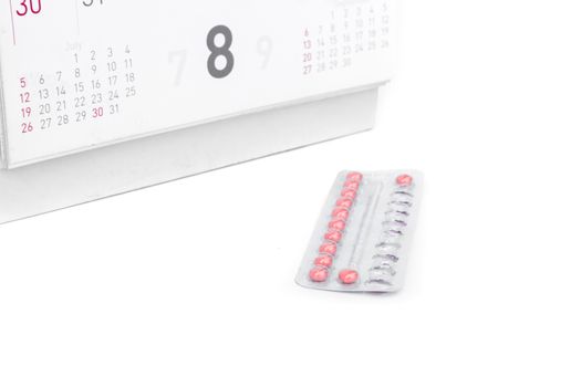 Close up birth-control pill with date of calendar background, health care and medicine concept