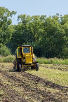 Tractor on the field plows the land, Russia, village, summer