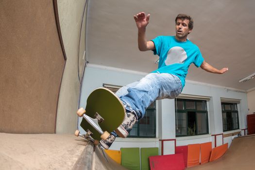 Skateboarder performing a trick on mini ramp at indoor skate park.