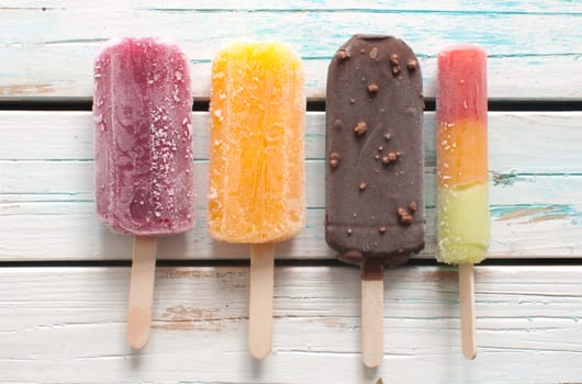Assorted ice popsicles over wooden background