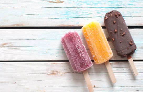 Assorted flavored ice lollies over a wooden background