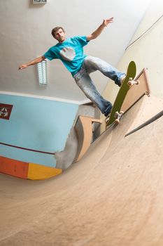Skateboarder performing a trick on mini ramp at indoor skate park.
