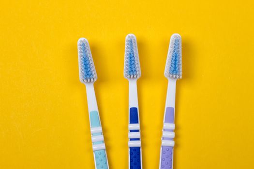 three Toothbrushes on the yellow background. Top view