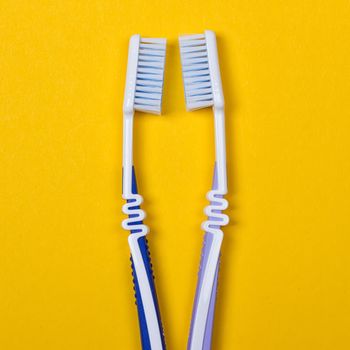 twi Toothbrushes on the yellow background. Top view