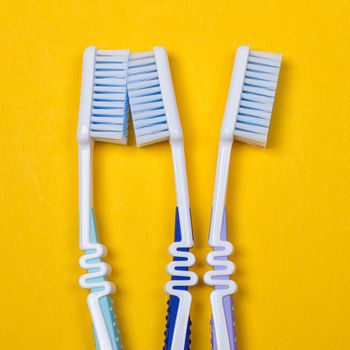 three Toothbrushes on the yellow background. Top view