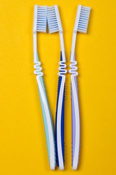 three Toothbrushes on the yellow background. Top view