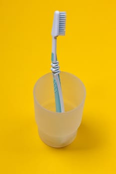 toothbrush in a glass on the yellow background. Top view