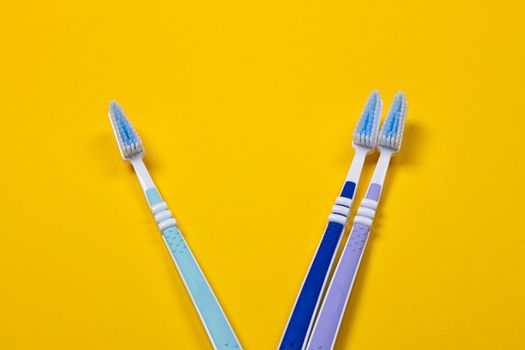 three Toothbrushes on the yellow background. Top view