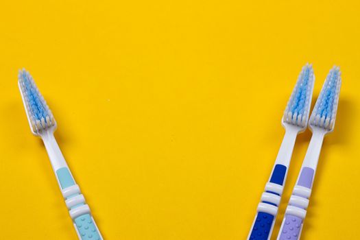 three Toothbrushes on the yellow background. Top view