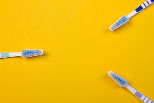 three Toothbrushes on the yellow background. Top view