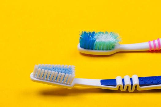Old used and new toothbrushes on the yellow background. Top view