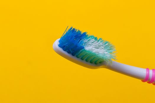 Old used toothbrush on the yellow background. Top view