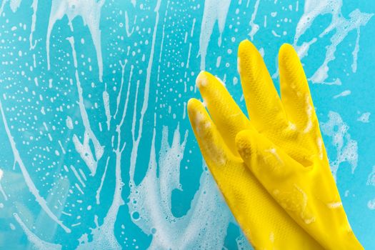 Cleaning concept, gloves in foam on a blue background