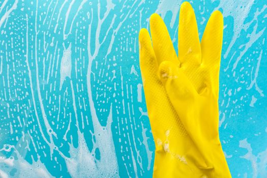 Cleaning concept, gloves in foam on a blue background