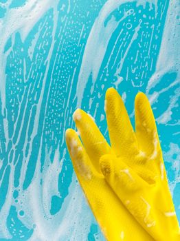 Cleaning concept, gloves in foam on a blue background