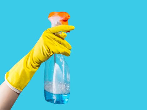 Detergent for cleaning in a female hand on blue background