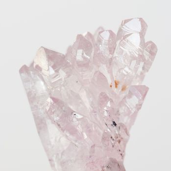 Beautiful cluster of transparent crystals of natural pink quartz gemstone amethyst on a white background