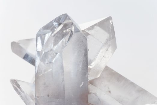 Cluster of several transparent quartz crystals close-up on a white background