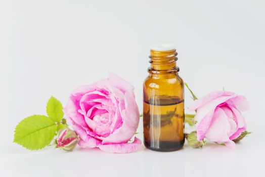 Vial with essential oil and two roses  isolated on a white background