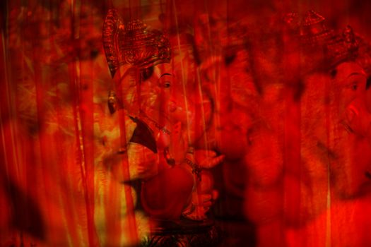 An abstract view of hindu elephant God Ganesha behind red transparent curtain