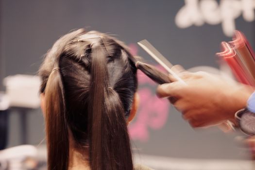 making coiffure with help of hair straightener, note shallow depth of field