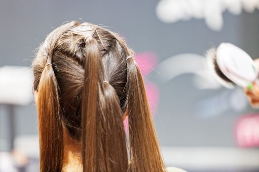 making coiffure with help of hair straightener, note shallow depth of field