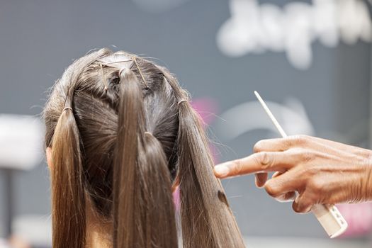 making coiffure with help of hair straightener, note shallow depth of field