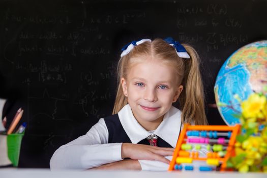 Smiling schoolgirl with globe near school blackboard