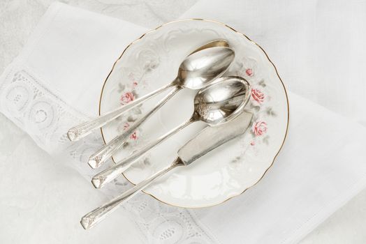 Top view of the beautifully table setting with white plate, lacy linen napkin and cutlery