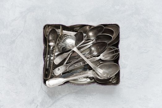 Various silverware in a metal tray on the background of gray concrete surface