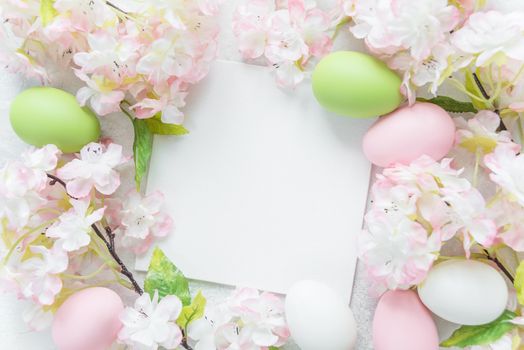 Beautiful delicate Easter frame with pink cherry flowers and multicolored Easter eggs