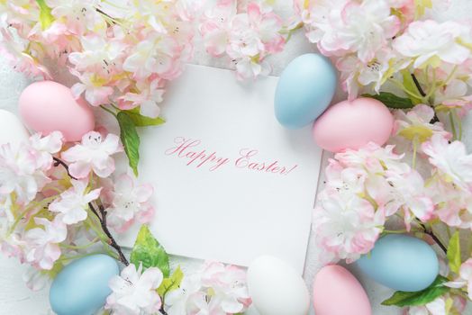 Beautiful delicate Easter frame with pink cherry flowers and multicolored Easter eggs, with  inscription "Happy Easter!"