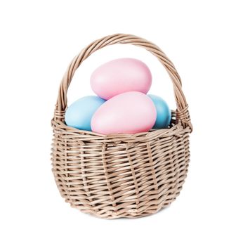 Wicker basket with pink and blue Easter eggs isolated on white background