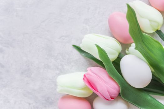 Easter composition with a bouquet of pink and white tulips and Easter eggs on the background of stone surface, with copy-space