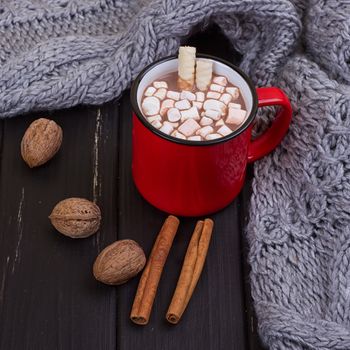 Hot cocoa with marshmallows with spices on the old wooden boards. Coffee, cocoa, cinnamon, nuts, cozy sweater. Autumn Still Life