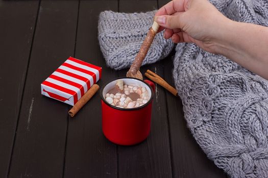 Autumn cappuccino composition. coffee cup top view with foam, cloves, cinnamon, present box and warm sweater at wood background. Fall hot drinks concept