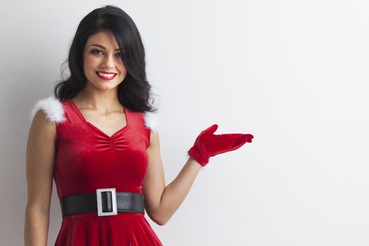 Young brunette christmas girl holding something on white background, copy space for text