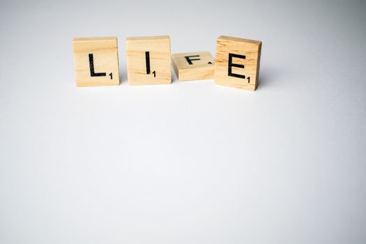 Scrabble tiles with word life/lie written on a white background