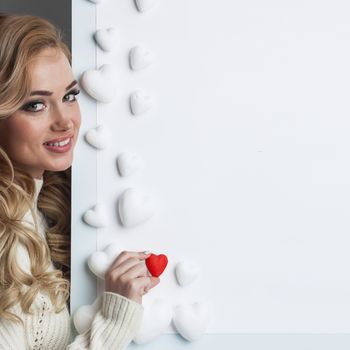 Young happy woman painting in red decorative hearts, Valentines day concept