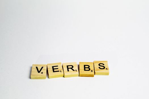 Scrabble tiles with word verbs written in a white background