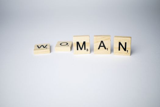 Scrabble tiles with word woman/man written on a white background to mind the differences between gender